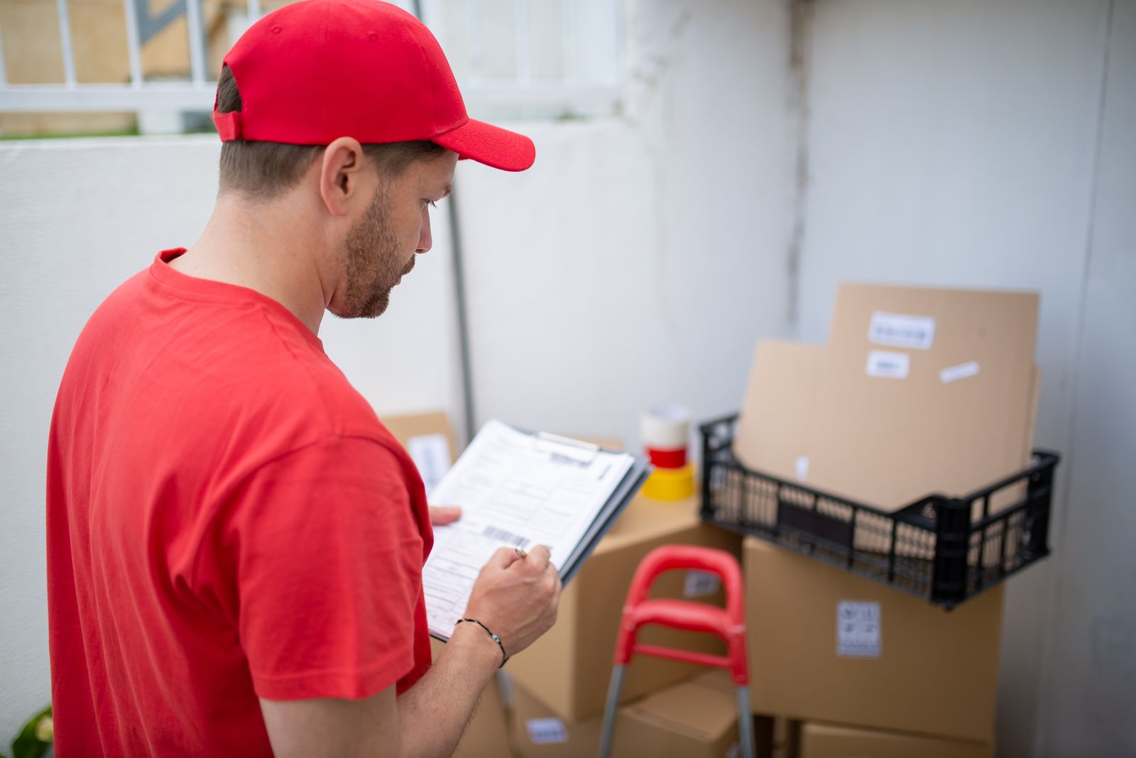 Delivery worker reviewing a schedule clipboard beside packages ready for dispatch
