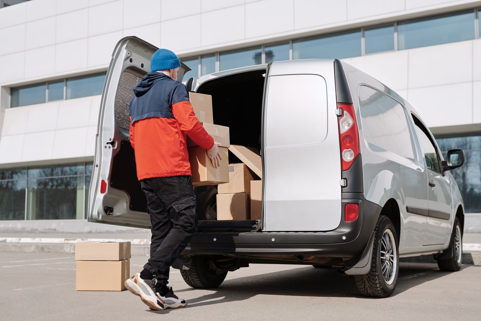 Delivery worker loading cardboard boxes into a van for daily dispatch