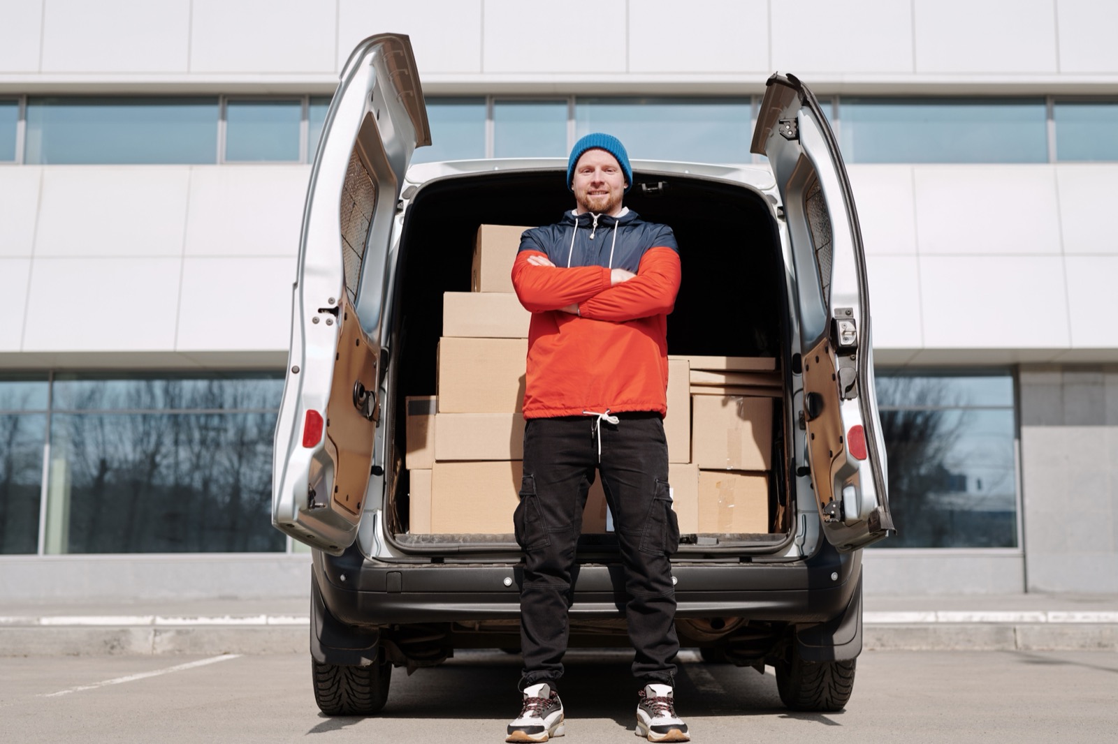 Owner of a small delivery business beside a van loaded with boxes on a city street